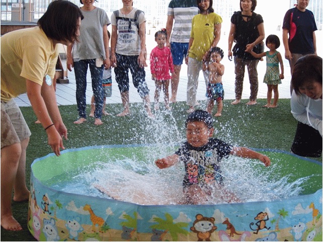 写真：板に乗ったままプールに落とされる子
