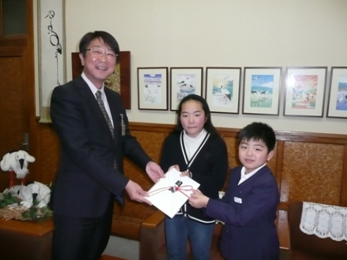 写真：あぐりキッズスクール受講生を代表して寄付をする田村さん（中央）と小林君