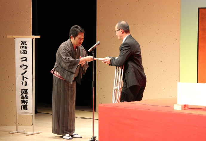 写真：舞台上で菊丸師匠から寄付を受け取る宮下課長