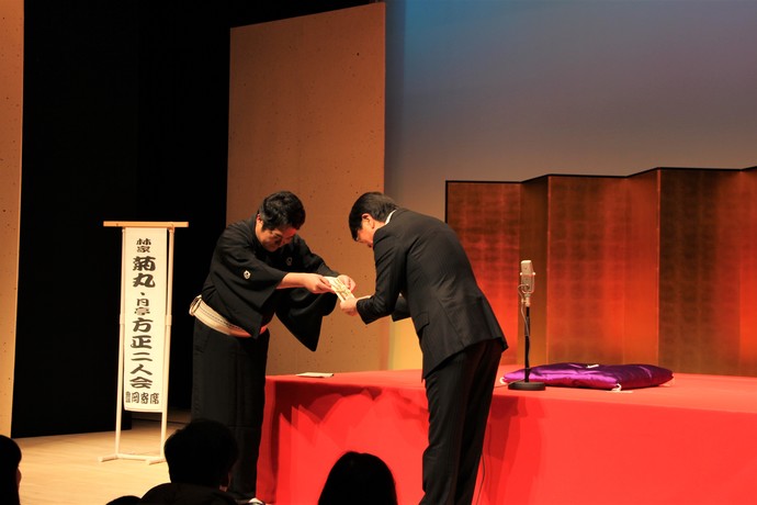 写真：舞台上で菊丸師匠から寄付を受け取る中貝市長
