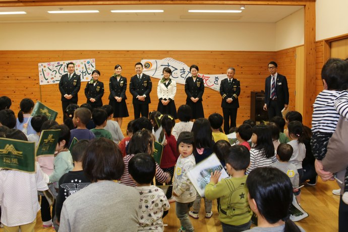 写真：会場前方に並ぶ7人の瑞風クルーと、後方にクラスごとに並ぶ園児