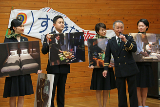 写真：食卓の写真パネルを持つ男性と、説明する列車長の長尾さん