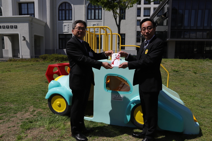 写真：寄贈された遊具の前で森田副市長が宝谷さんから目録を受け取る様子