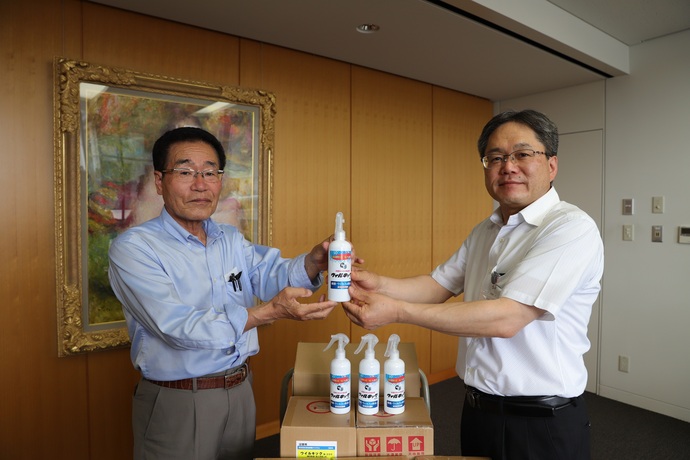 森田副市長が小田根清勝さんから除菌・消臭剤を受け取る様子