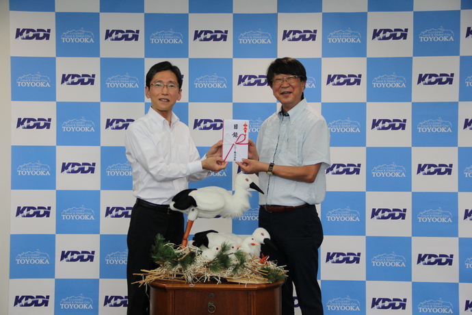 写真：KDDI株式会社関西総支社長の宇佐見典正さんが中貝市長に寄付を手渡す