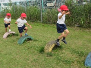 写真：タイヤの遊具を飛び越えたりしながら遊んでいる園児の様子