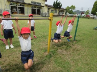 鉄棒にぶら下がって遊ぶ園児の写真