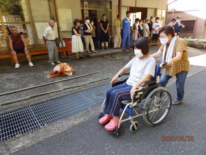 写真：谷山区　車いすを使用した搬送訓練の様子