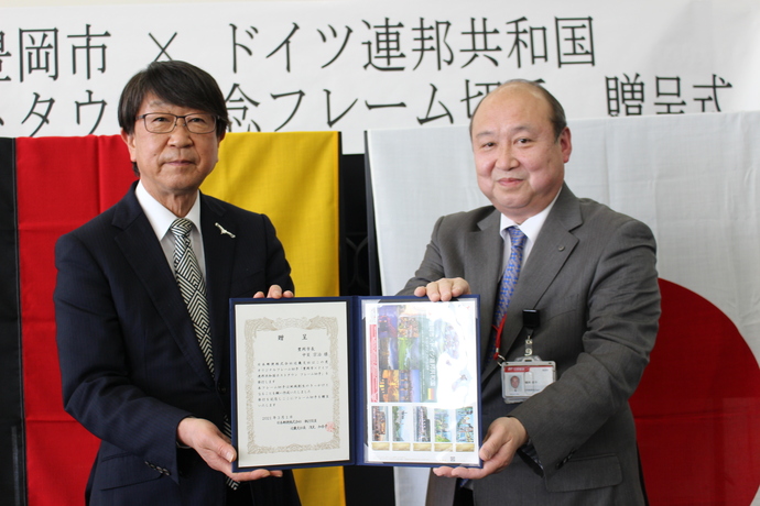 ホストタウン記念フレーム切手を手にする中貝市長(左)と竹野郵便局長 織田恭平さん(右)の写真