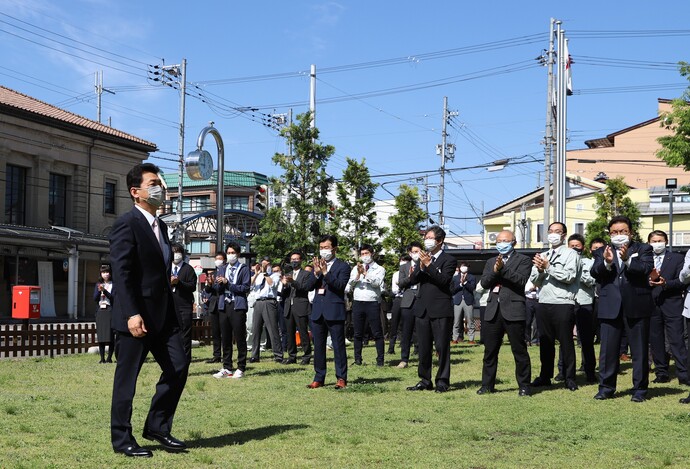 写真：市役所前で職員や市民に拍手で出迎えられる関貫新市長