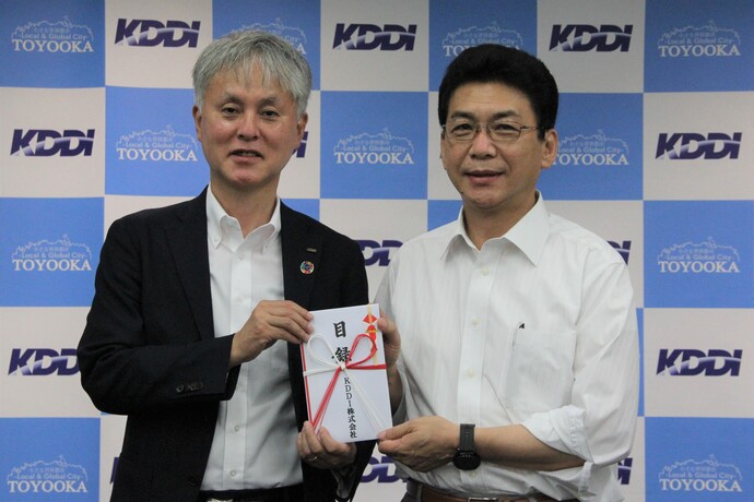 写真:KDDI株式会社理事関西総支社長の田中稔さんが関貫市長に寄付目録を手渡す