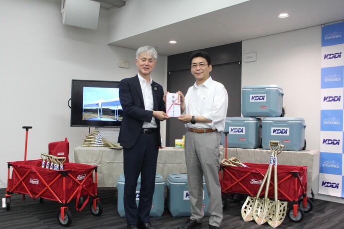 寄付物品の前でKDDI株式会社理事関西総支社長の田中稔さんと関貫市長