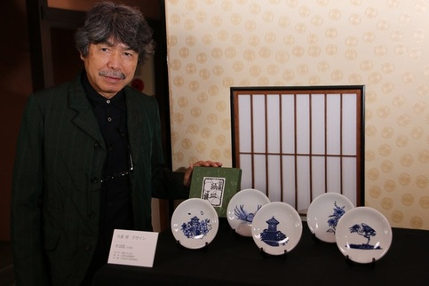 写真：自身がデザインした切り絵皿そばを披露する久保さん
