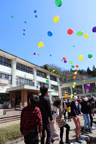 写真：校舎を背景に風船を飛ばす生徒たち