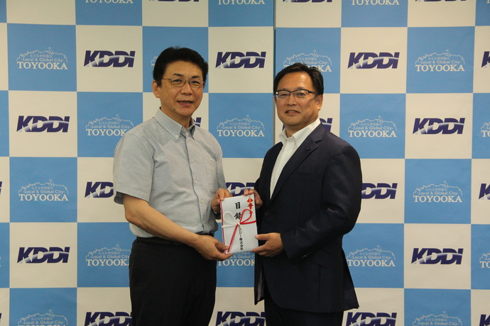 写真：KDDI株式会社理事関西総支社長の江口高介さんが関貫市長に寄付目録を手渡す