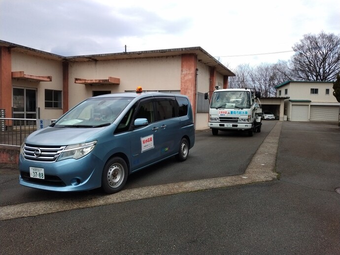 写真：出発する補助車（ワゴンタイプの乗用車）と給水車