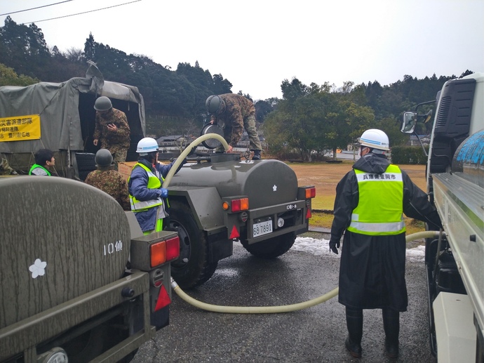 写真：自衛隊の車両にホースをつなぐ豊岡市の給水車