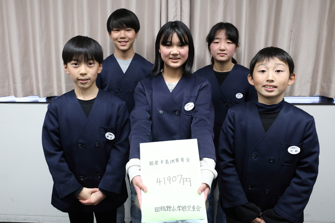 写真：田鶴野小学校児童会の5人が寄付金の袋を持っている