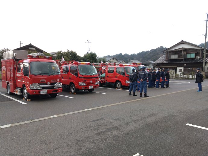 パレード出発前に消防団長から注意事項等の指示を受ける団員と車両