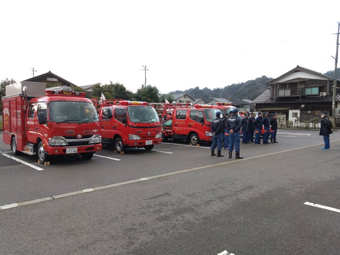 パレード出発前に消防団長から注意事項等の指示を受ける団員と車両