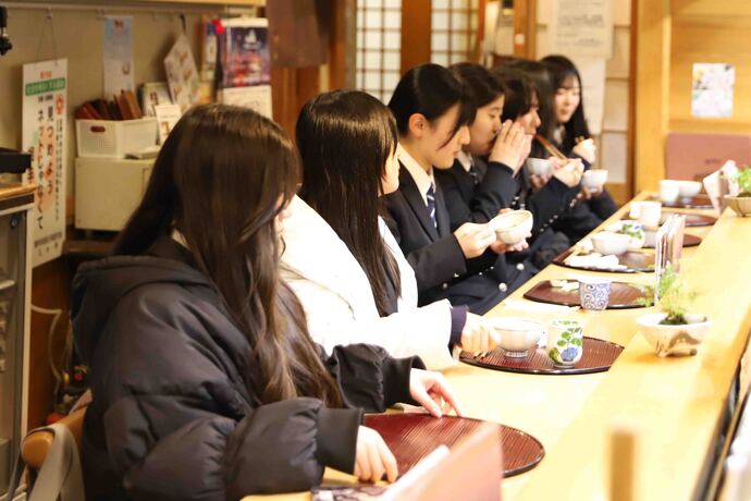 画像：カウンターに並んで食事をする高校生