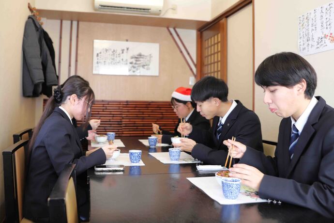 画像：テーブルで食事する高校生