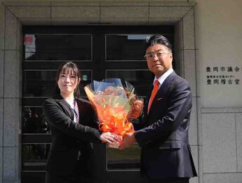 写真：花束を受け取り、笑顔を向ける門間市長