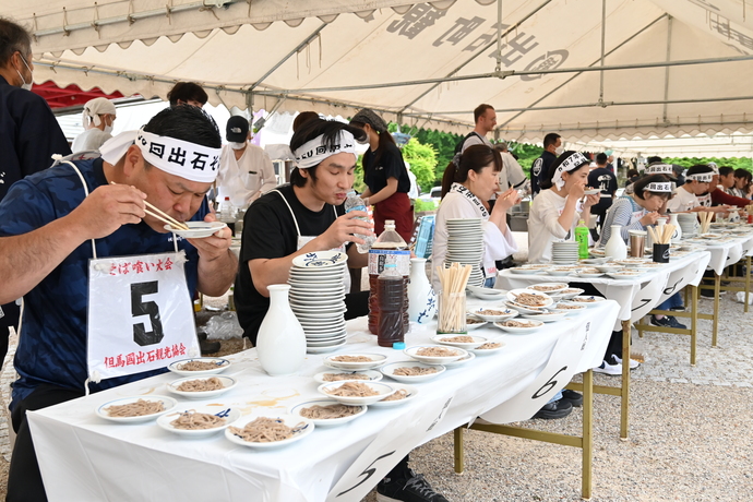 写真：椅子に座って出石そばを食べている選手たち