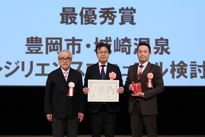 写真：左から、審査委員の中林一樹氏（東京都立大学名誉教授／日本災害復興学会 特別顧問）、冨岡　隆豊岡市城崎振興局長、検討会議議長の松井裕一朗氏